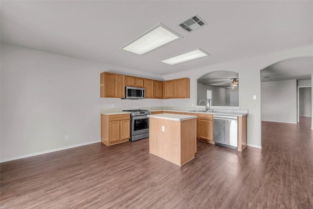 100 Grant Cv, Hutto, TX 78634 - kitchen with appliances with stainless steel finishes, arched walkways, light countertops, open floor plan, and dark wood-style flooring