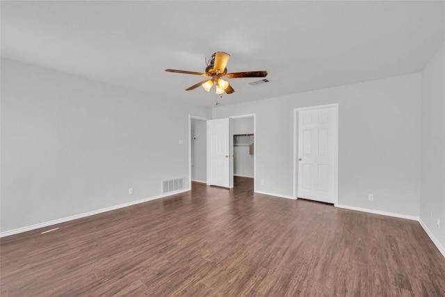 100 Grant Cv, Hutto, TX 78634 - unfurnished bedroom featuring dark wood finished floors, a ceiling fan, a closet, and a spacious closet