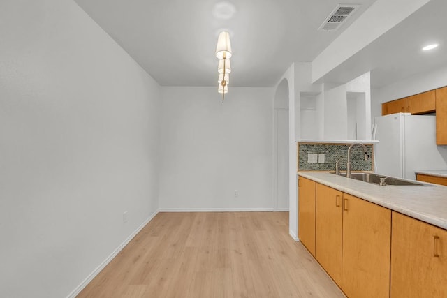 10616 Mellow Mdws Unit 17A, Austin, TX 78750 - kitchen with freestanding refrigerator, light wood-style floors, light countertops, arched walkways, and backsplash