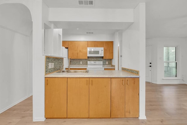 10616 Mellow Mdws Unit 17A, Austin, TX 78750 - kitchen featuring white appliances, light wood-style floors, a peninsula, tasteful backsplash, and light countertops