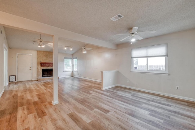 4901 Transit Cir, Austin, TX 78727 - unfurnished living room with a textured ceiling, light wood-type flooring, ceiling fan, a large fireplace, and vaulted ceiling