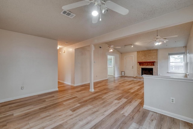 4901 Transit Cir, Austin, TX 78727 - unfurnished living room featuring ceiling fan, a fireplace, light wood-type flooring, and track lighting