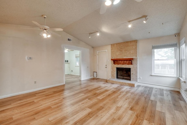 4901 Transit Cir, Austin, TX 78727 - unfurnished living room featuring ceiling fan, light wood-type flooring, a fireplace, lofted ceiling, and a textured ceiling