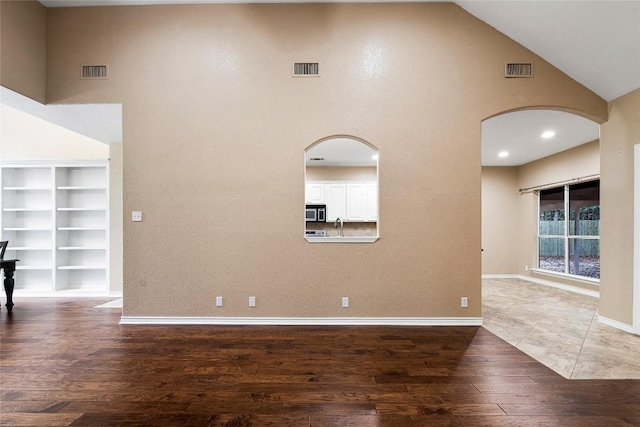 230 Cedar Hills Dr, Elgin, TX 78621 - unfurnished room featuring arched walkways, high vaulted ceiling, wood finished floors, and built in shelves