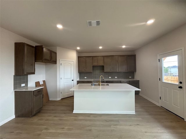 627 Palo Brea Loop, Hutto, TX 78634 - kitchen with decorative backsplash, an island with sink, light wood finished floors, and recessed lighting