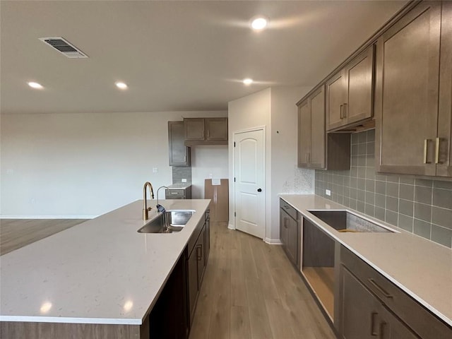 627 Palo Brea Loop, Hutto, TX 78634 - kitchen with black electric stovetop, light wood-style flooring, decorative backsplash, recessed lighting, and a center island with sink