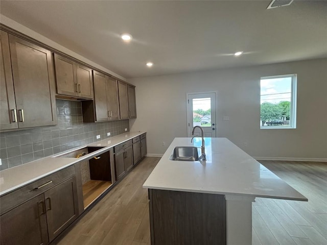 627 Palo Brea Loop, Hutto, TX 78634 - kitchen featuring black electric cooktop, a kitchen island with sink, light wood-style floors, decorative backsplash, and recessed lighting