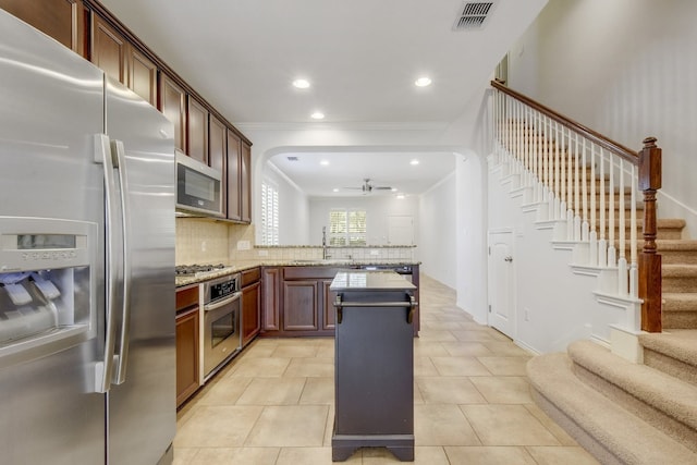 1209 Salem Park Ct, Austin, TX 78745 - kitchen with appliances with stainless steel finishes, a ceiling fan, crown molding, a peninsula, and decorative backsplash