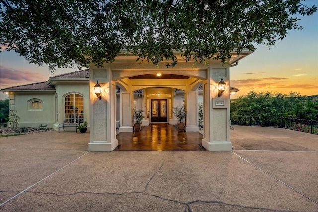 1307 Osprey Ridge Loop, Lago Vista, TX 78645 - exterior entry at dusk with french doors, stucco siding, and a tiled roof
