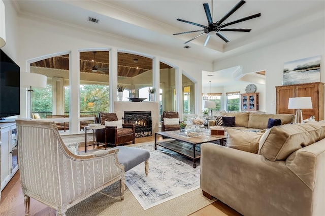 1307 Osprey Ridge Loop, Lago Vista, TX 78645 - living room featuring a ceiling fan, a lit fireplace, ornamental molding, wood finished floors, and a chandelier