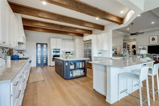 1307 Osprey Ridge Loop, Lago Vista, TX 78645 - kitchen with white cabinetry, appliances with stainless steel finishes, open floor plan, a ceiling fan, and beamed ceiling