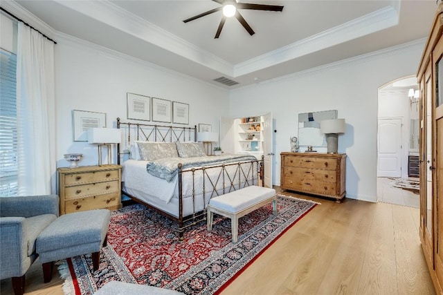 1307 Osprey Ridge Loop, Lago Vista, TX 78645 - bedroom featuring wood finished floors, arched walkways, crown molding, a tray ceiling, and a ceiling fan