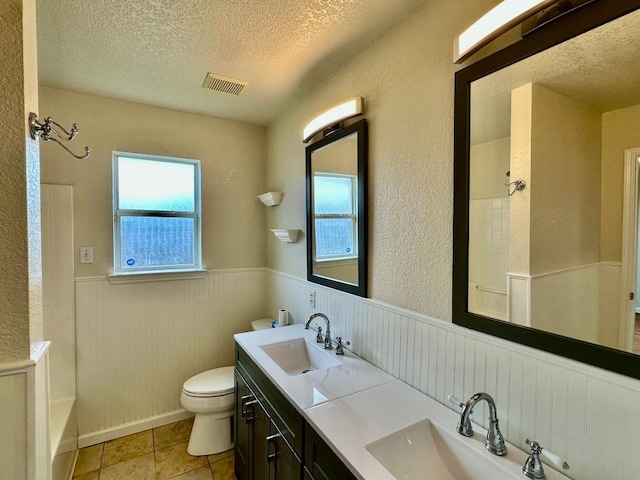3303 Solomon Dr, Killeen, TX 76542 - bathroom featuring a textured ceiling, a wainscoted wall, healthy amount of natural light, double vanity, and tile patterned flooring