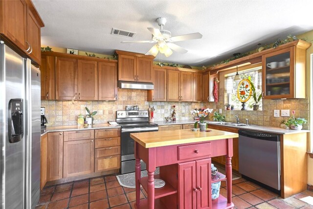 21013 Fawn Ridge Dr, Lago Vista, TX 78645 - kitchen featuring appliances with stainless steel finishes, under cabinet range hood, wood counters, ceiling fan, and tasteful backsplash