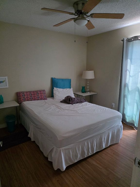 2124 Burton Dr Unit 208, Austin, TX 78741 - bedroom with wood finished floors, a textured ceiling, and a ceiling fan