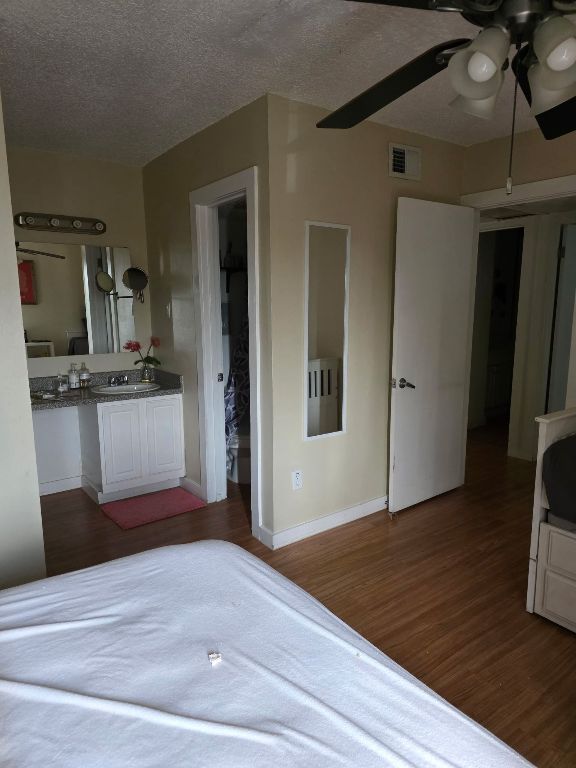 2124 Burton Dr Unit 208, Austin, TX 78741 - bedroom with wood finished floors, a textured ceiling, and a ceiling fan