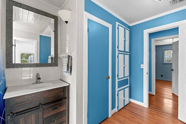 130 Anderson Ln, Red Rock, TX 78662 - bathroom with wood finished floors, vanity, plenty of natural light, tasteful backsplash, and ornamental molding
