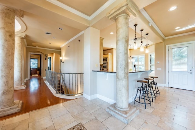 5120 Mansfield View Ct, Austin, TX 78732 - kitchen featuring ornate columns, a kitchen bar, ornamental molding, stainless steel oven, and decorative light fixtures
