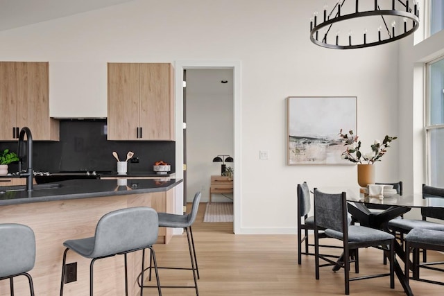 1817 High Lonesome, Leander, TX 78641 - kitchen with light brown cabinets, light wood-style flooring, dark countertops, backsplash, and a breakfast bar