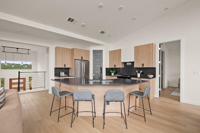 1817 High Lonesome, Leander, TX 78641 - kitchen featuring freestanding refrigerator, a breakfast bar, light brown cabinets, dark countertops, and high vaulted ceiling