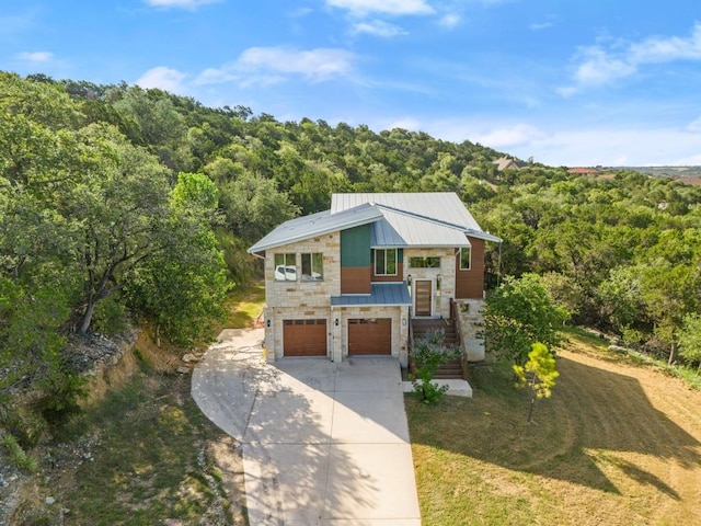 1817 High Lonesome, Leander, TX 78641 - modern home with stone siding, a forest view, concrete driveway, and an attached garage