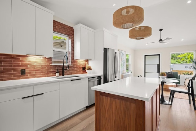3704 Munson St Unit 1, Austin, TX 78721 - kitchen featuring light wood finished floors, backsplash, stainless steel appliances, light countertops, and ceiling fan
