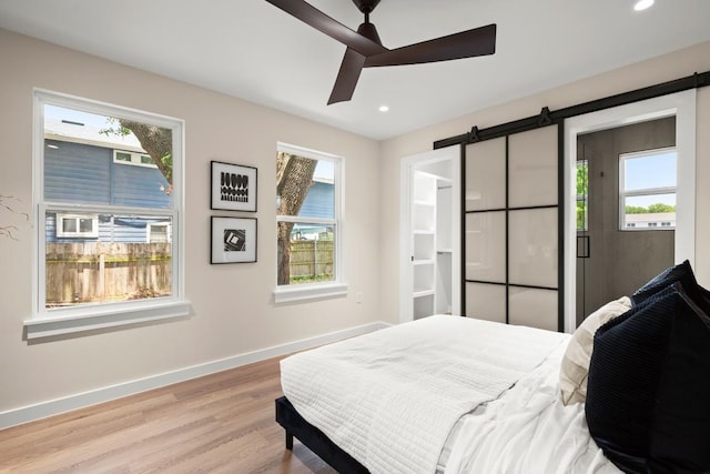 3704 Munson St Unit 1, Austin, TX 78721 - bedroom featuring a barn door, light wood-style flooring, multiple windows, and recessed lighting