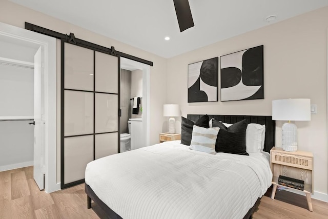 3704 Munson St Unit 1, Austin, TX 78721 - bedroom featuring a barn door, wood finished floors, recessed lighting, ensuite bath, and ceiling fan