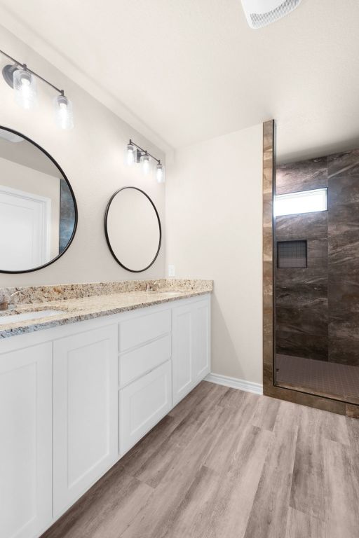 817 Coke Rd, Burnet, TX 78611 - full bathroom with double vanity, walk in shower, and wood finished floors