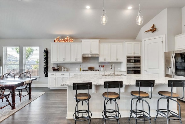 2817 Mossy Springs Dr, Leander, TX 78641 - kitchen with appliances with stainless steel finishes, backsplash, vaulted ceiling, white cabinets, and a kitchen island with sink