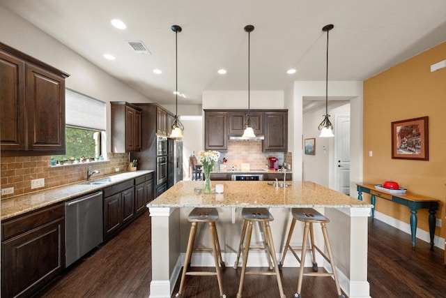 29 Prestonwood Cir, Lakeway, TX 78734 - kitchen with appliances with stainless steel finishes, dark wood finished floors, dark brown cabinets, a kitchen island with sink, and a kitchen breakfast bar
