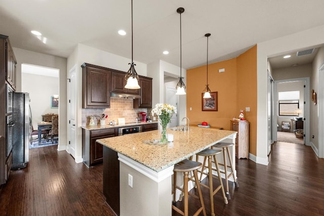 29 Prestonwood Cir, Lakeway, TX 78734 - kitchen with dark brown cabinets, dark wood-type flooring, under cabinet range hood, backsplash, and recessed lighting