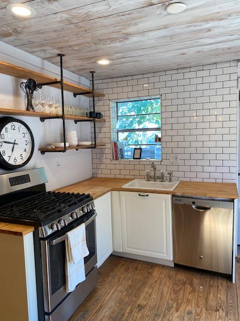 1305 Salina St Unit 1, Austin, TX 78702 - kitchen with stainless steel appliances, wood counters, wood ceiling, white cabinetry, and open shelves