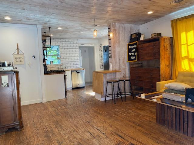 1305 Salina St Unit 1, Austin, TX 78702 - kitchen with stainless steel dishwasher, wood finished floors, freestanding refrigerator, a kitchen breakfast bar, and wood ceiling