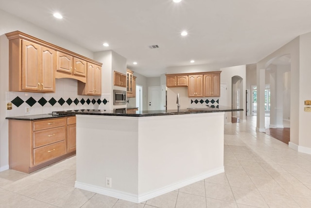 11208 Cedarcliffe Dr, Austin, TX 78750 - kitchen with stainless steel microwave, arched walkways, decorative backsplash, dark countertops, and light tile patterned flooring