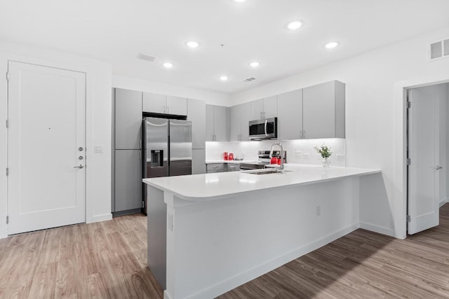 4801 Springdale Dr Unit 2010, Austin, TX 78723 - kitchen featuring appliances with stainless steel finishes, gray cabinets, a peninsula, light countertops, and light wood finished floors