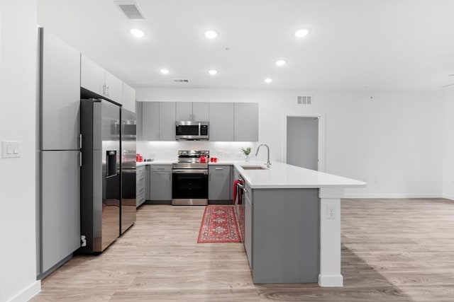 4801 Springdale Dr Unit 2010, Austin, TX 78723 - kitchen featuring appliances with stainless steel finishes, gray cabinetry, a peninsula, light wood-style floors, and recessed lighting