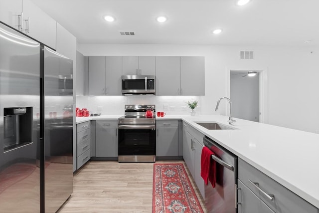 4801 Springdale Dr Unit 2010, Austin, TX 78723 - kitchen with appliances with stainless steel finishes, gray cabinetry, light wood-style flooring, decorative backsplash, and recessed lighting