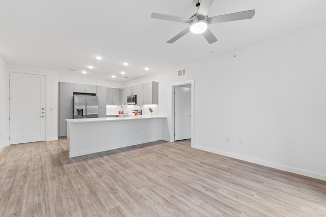 4801 Springdale Dr Unit 2010, Austin, TX 78723 - kitchen with appliances with stainless steel finishes, gray cabinetry, a peninsula, light countertops, and light wood-type flooring