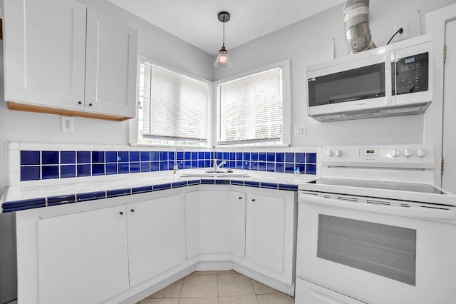15102 Iowa St, Austin, TX 78734 - kitchen featuring white range with electric cooktop, stainless steel microwave, tile countertops, and white cabinets