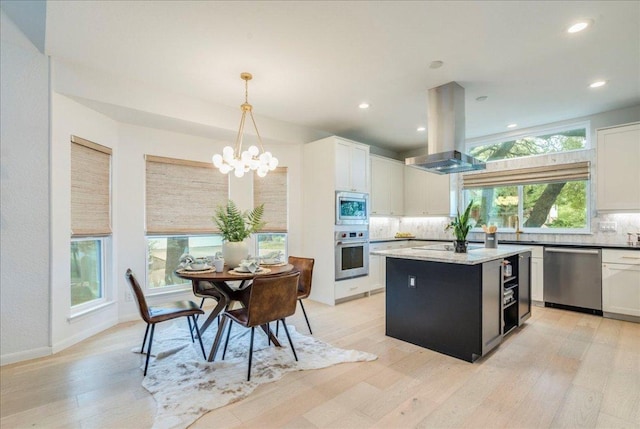 9110 Scotsman Dr, Austin, TX 78750 - kitchen with island range hood, appliances with stainless steel finishes, a chandelier, backsplash, and light wood-style flooring
