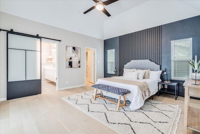 9110 Scotsman Dr, Austin, TX 78750 - bedroom with a barn door, wood finished floors, connected bathroom, high vaulted ceiling, and a ceiling fan