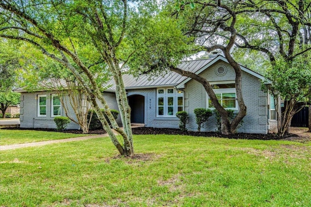 9110 Scotsman Dr, Austin, TX 78750 - view of front of home with a standing seam roof, brick siding, a front lawn, and a metal roof