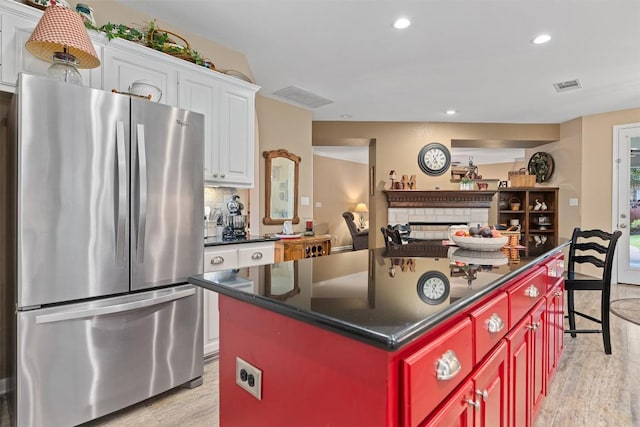 35 Forest Mesa, Round Rock, TX 78664 - kitchen featuring freestanding refrigerator, light wood-style flooring, dark countertops, white cabinets, and a fireplace