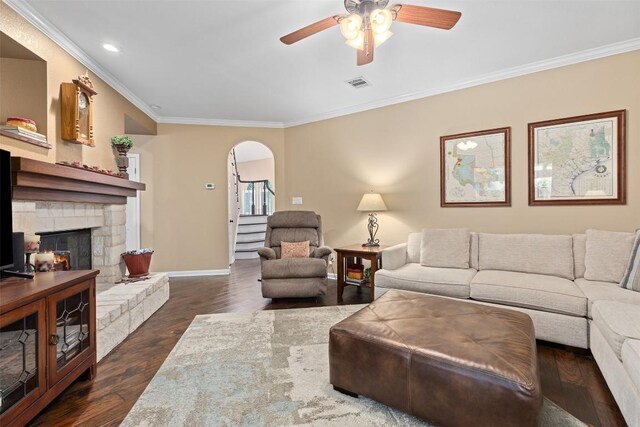 35 Forest Mesa, Round Rock, TX 78664 - living room with a fireplace, crown molding, a ceiling fan, dark wood-style floors, and arched walkways