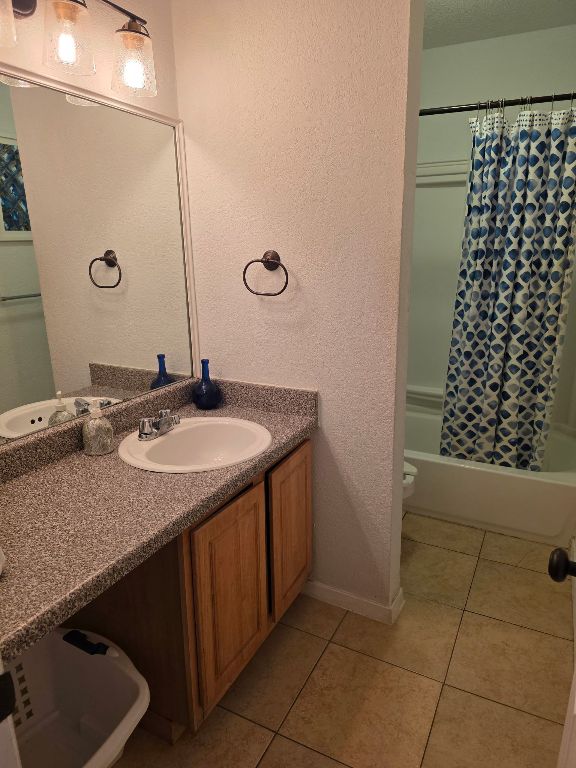 2124 Burton Dr Unit 116, Austin, TX 78741 - bathroom featuring vanity, shower / bath combo with shower curtain, tile patterned floors, and a textured wall