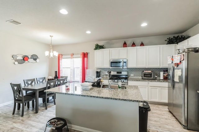 18430 Stevie Ray Dr, Round Rock, TX 78664 - kitchen featuring appliances with stainless steel finishes, light wood-style floors, white cabinets, a chandelier, and light stone countertops