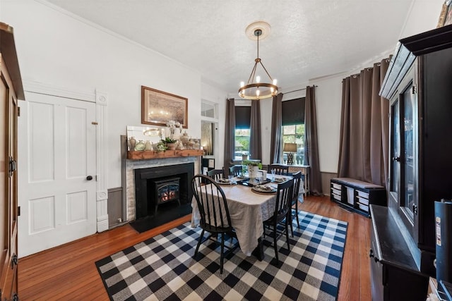 404 E 9th Ave, Belton, TX 76513 - dining space featuring a chandelier, wood finished floors, a textured ceiling, a fireplace with flush hearth, and crown molding