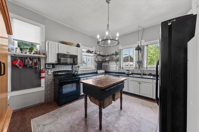 404 E 9th Ave, Belton, TX 76513 - kitchen featuring black appliances, dark countertops, a chandelier, a textured ceiling, and light wood finished floors