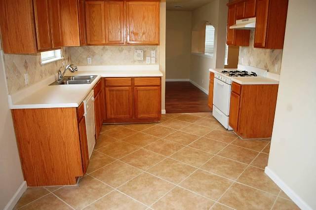 205 E Mitchell Dr, Hutto, TX 78634 - kitchen featuring white range with gas cooktop, under cabinet range hood, decorative backsplash, light countertops, and brown cabinets